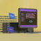 Hosting en España: cómo elegir el mejor para tu negocio Computadora con símbolos de programación HTML, CSS, PHP, y JavaScript sobre fondo amarillo. Codificación digital.
