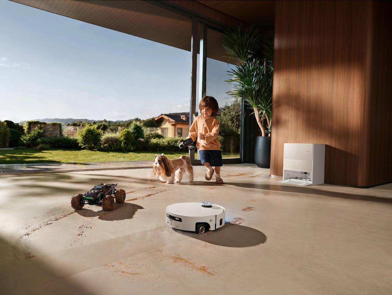 Niño jugando con perro mientras robot aspirador limpia suelos en casa moderna.
