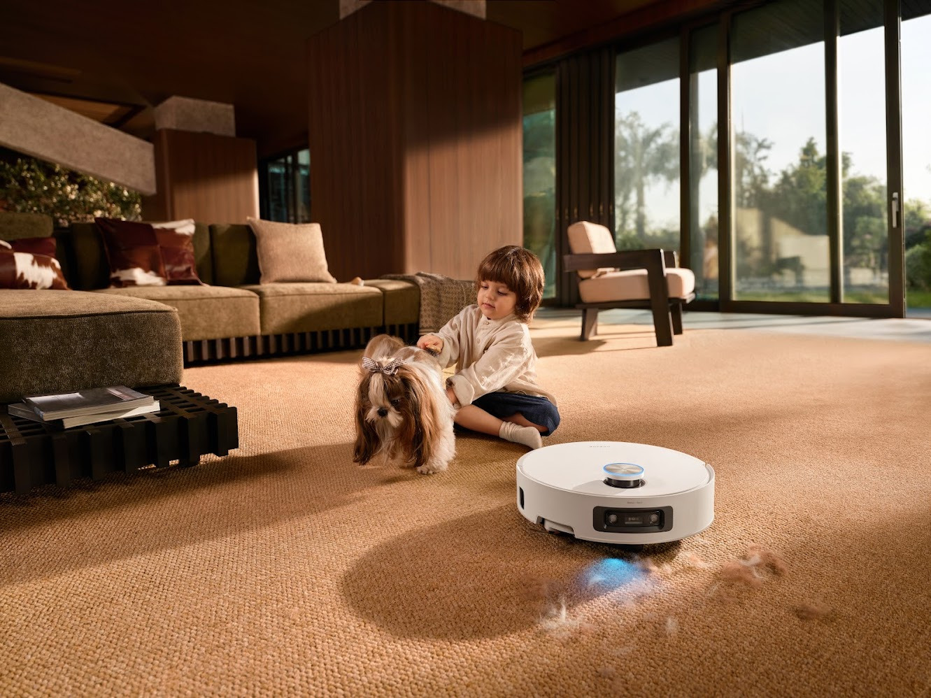 Niño con perro en sala moderna mientras robot aspiradora limpia alfombra.