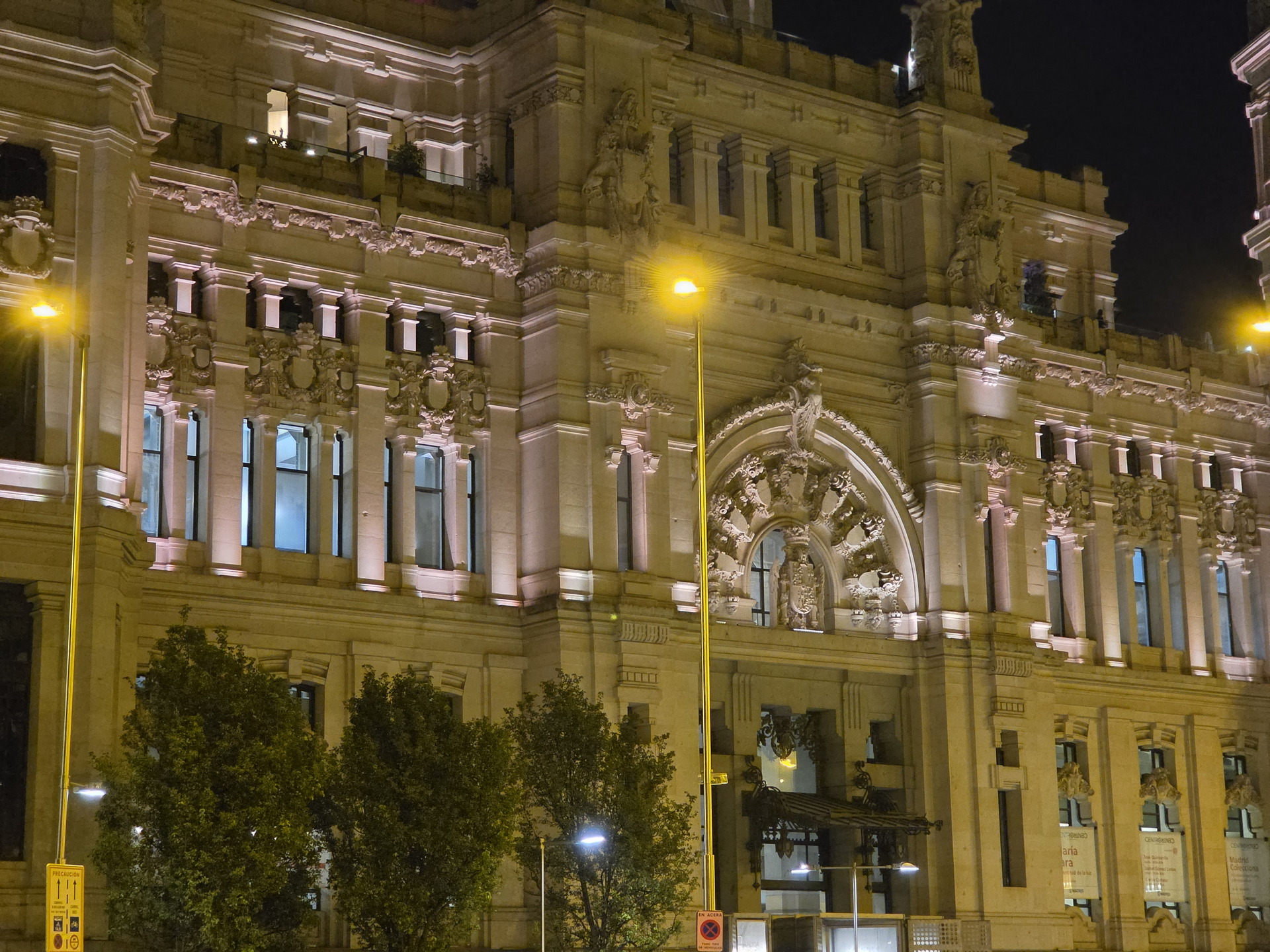 Edificio histórico iluminado por la noche en Madrid, destacando su arquitectura detallada y majestuosa.