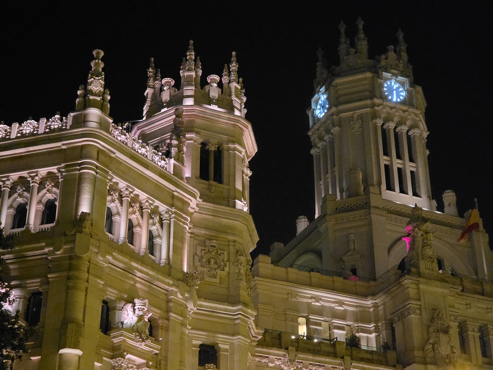 Vista nocturna del Palacio de Cibeles iluminado, destacando sus detalles arquitectónicos en Madrid.
