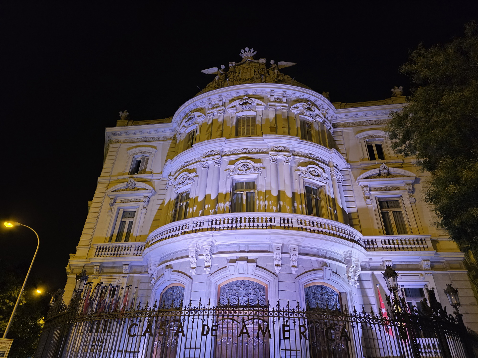 Fachada de la Casa de América iluminada por la noche en Madrid, destacando su arquitectura clásica.