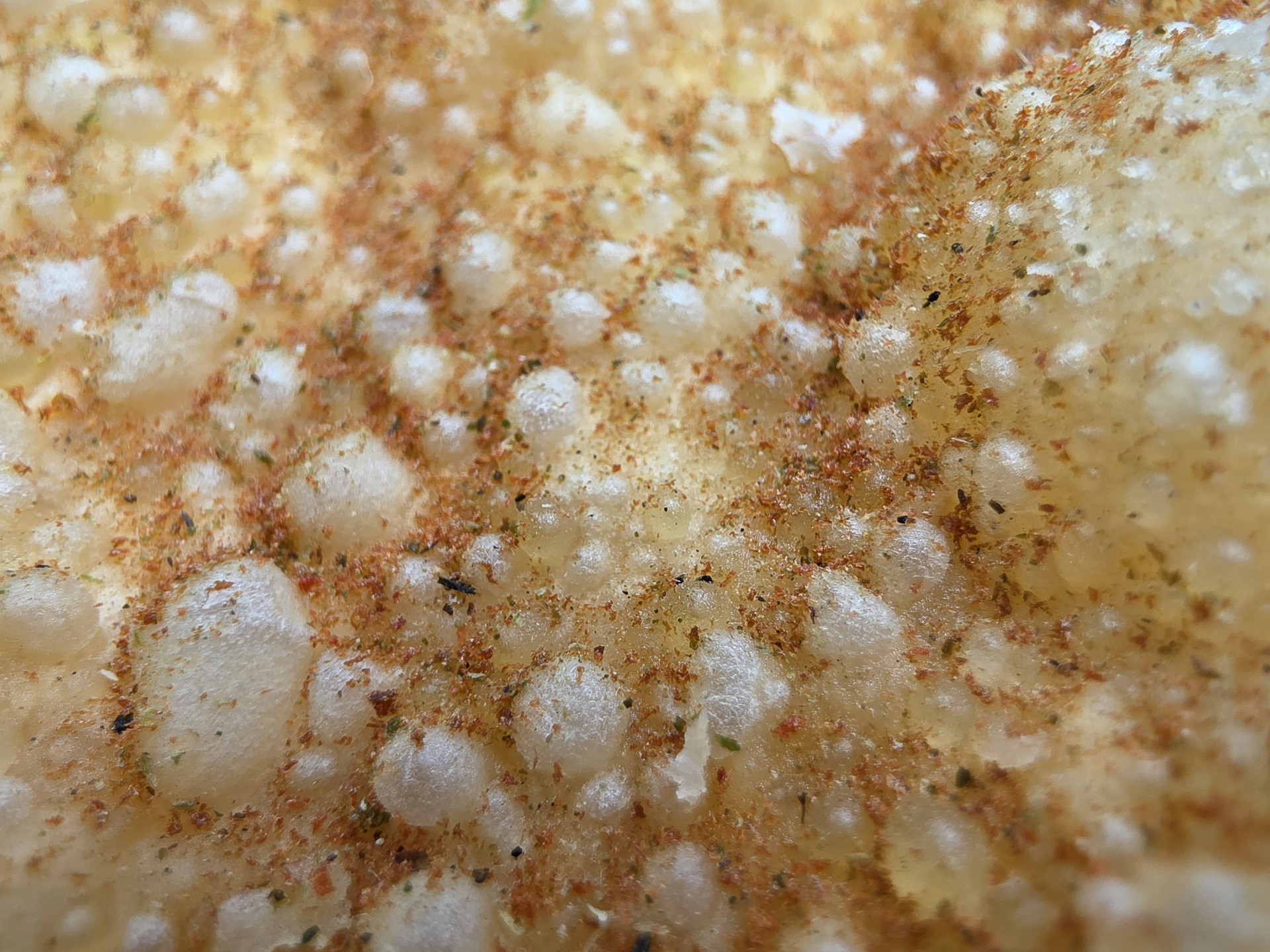 Textura granulada con especias sobre superficie dorada, vista macro. Ideal para fondo de comida o cocina.