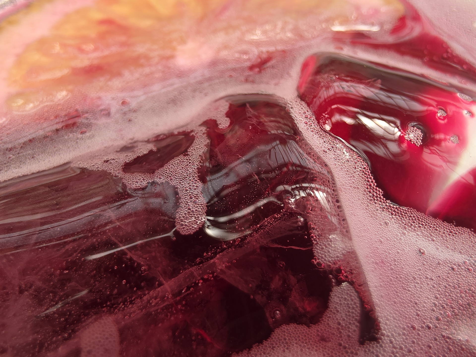Bebida refrescante de fruta roja con espuma y cubos de hielo.