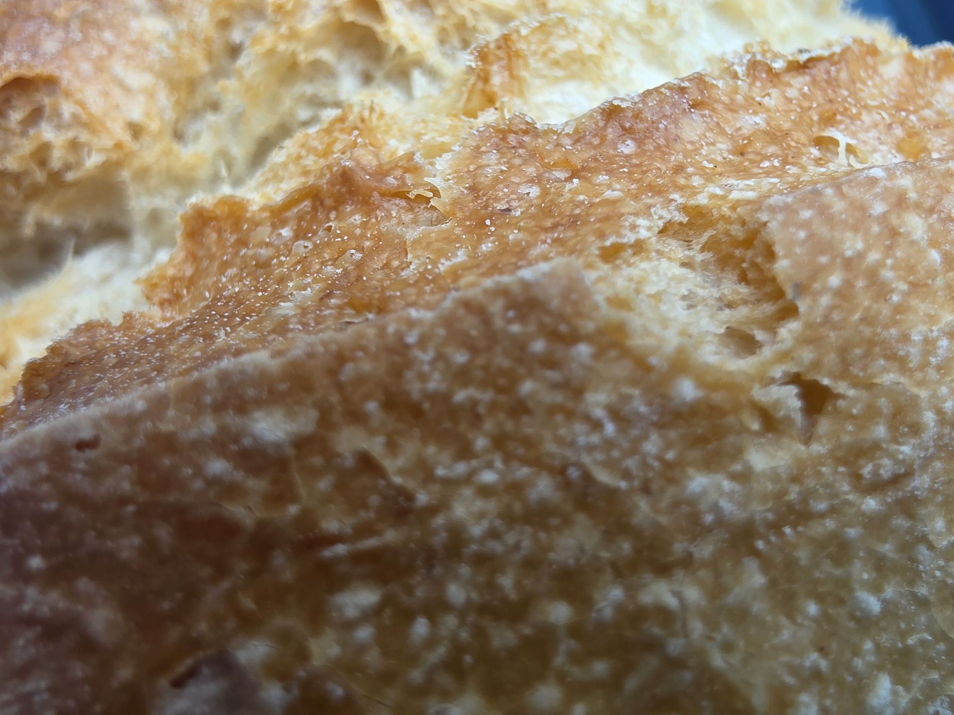 Primer plano de corteza de pan recién horneado con textura dorada y crujiente.