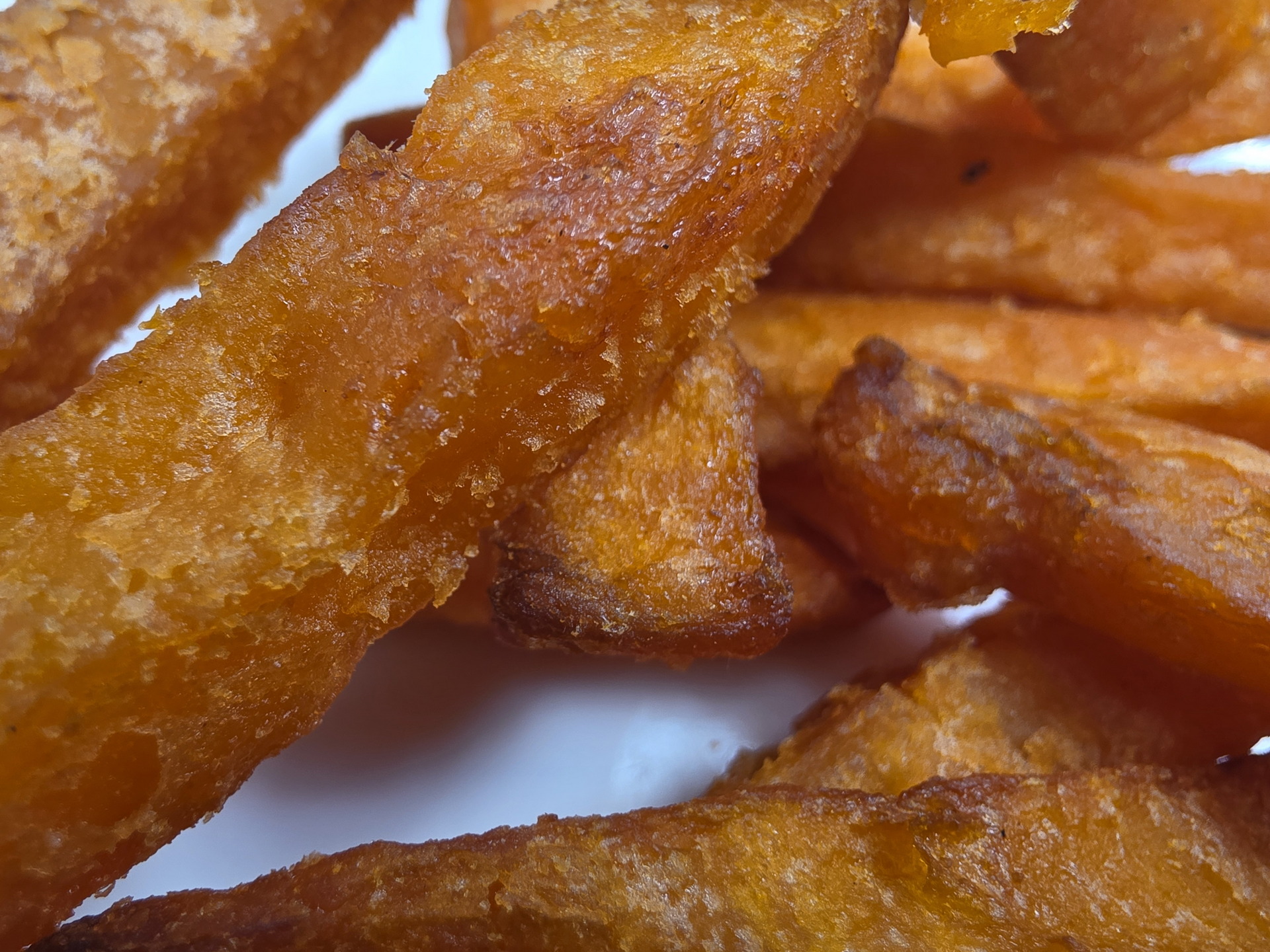 Papas fritas de camote crujientes, doradas y recién cocinadas, servidas en un plato blanco.