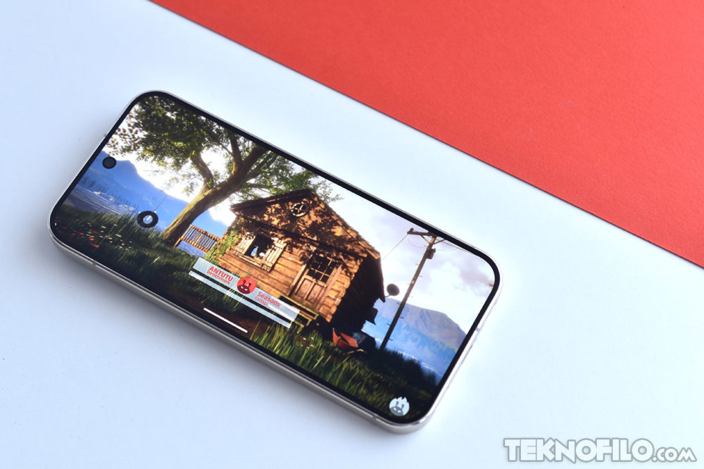 Smartphone mostrando juego de cabaña en pantalla, sobre fondo rojo y blanco.