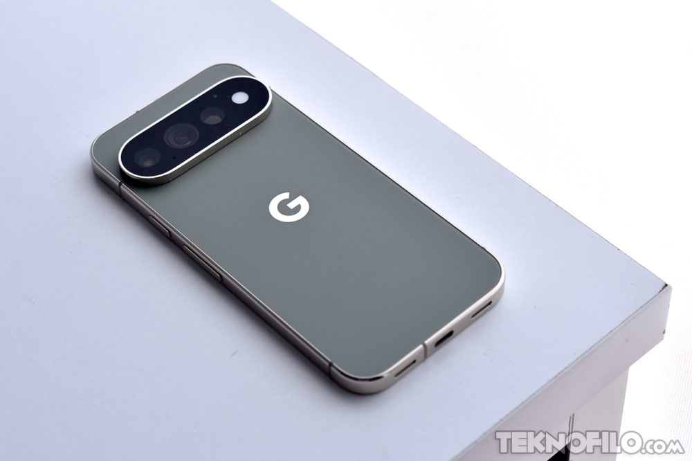 Smartphone Google Pixel verde sobre una superficie blanca, mostrando su cámara trasera avanzada y diseño elegante.