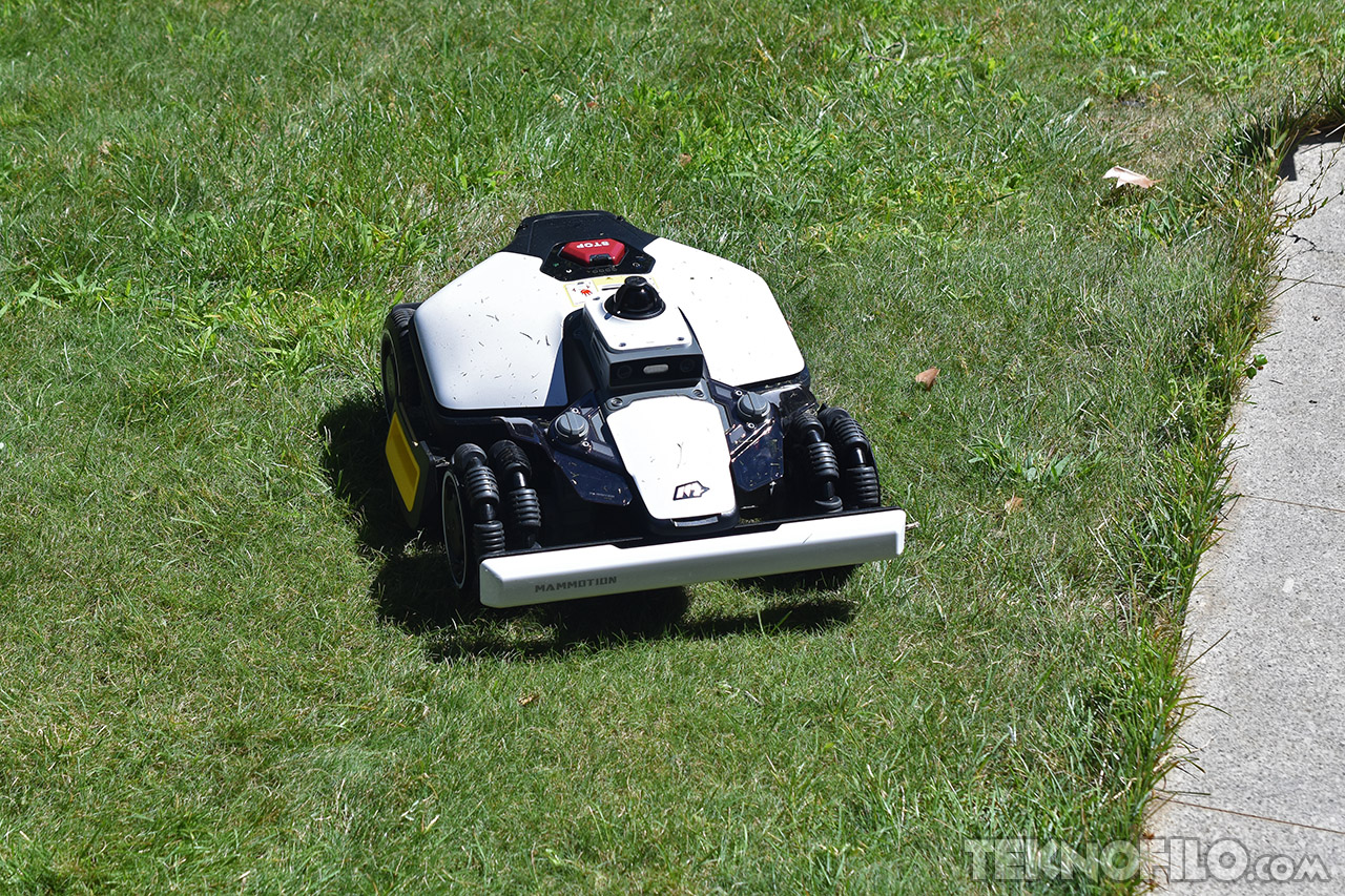 Robot cortacésped autónomo en acción sobre césped verde en un día soleado.