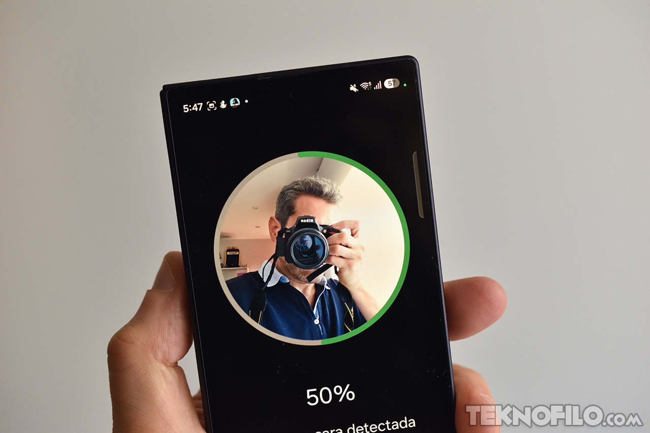 Usuario sosteniendo un smartphone que muestra una imagen con un progreso del 50% en la detección de la cámara.