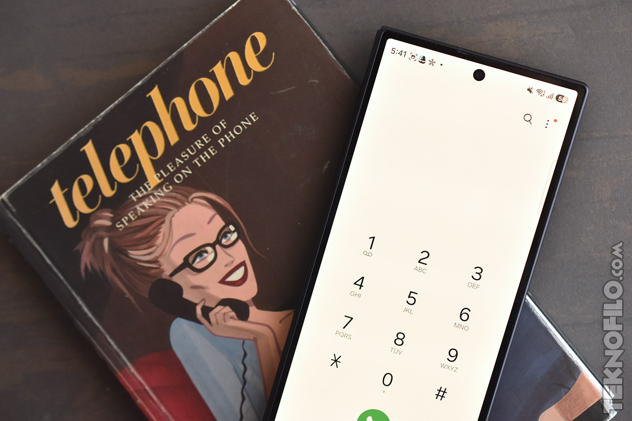 Smartphone con pantalla de marcación sobre un libro vintage de teléfonos.