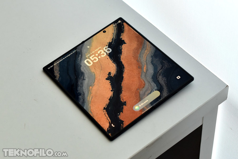 Samsung revela el secreto del la serie Galaxy Z Fold 8: una pantalla con titanio 20 veces más rígida Pantalla de smartphone plegable con diseño artístico abstracto sobre una mesa blanca.