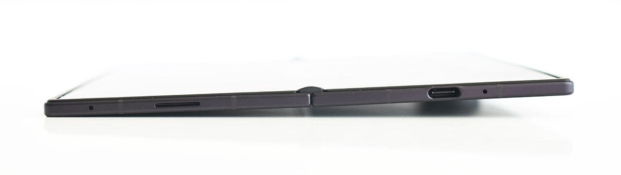 Dispositivo móvil plegable visto de perfil con puerto USB-C y diseño delgado.