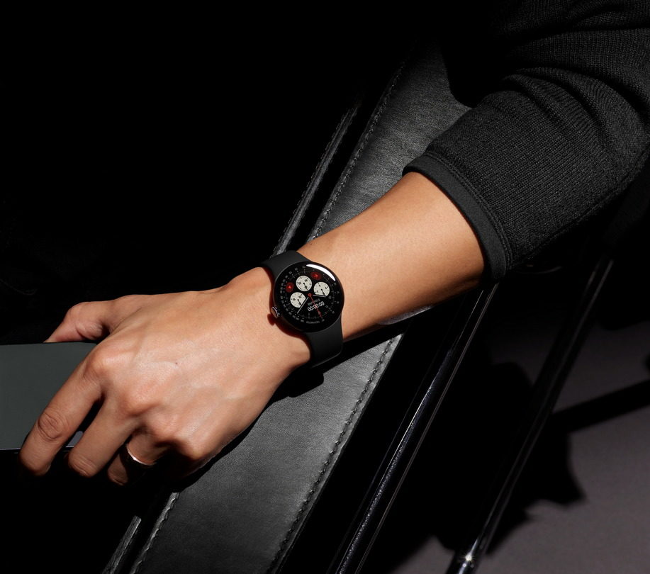 Mano con reloj inteligente de diseño elegante sobre fondo negro iluminado, destacando la esfera y el brazalete.