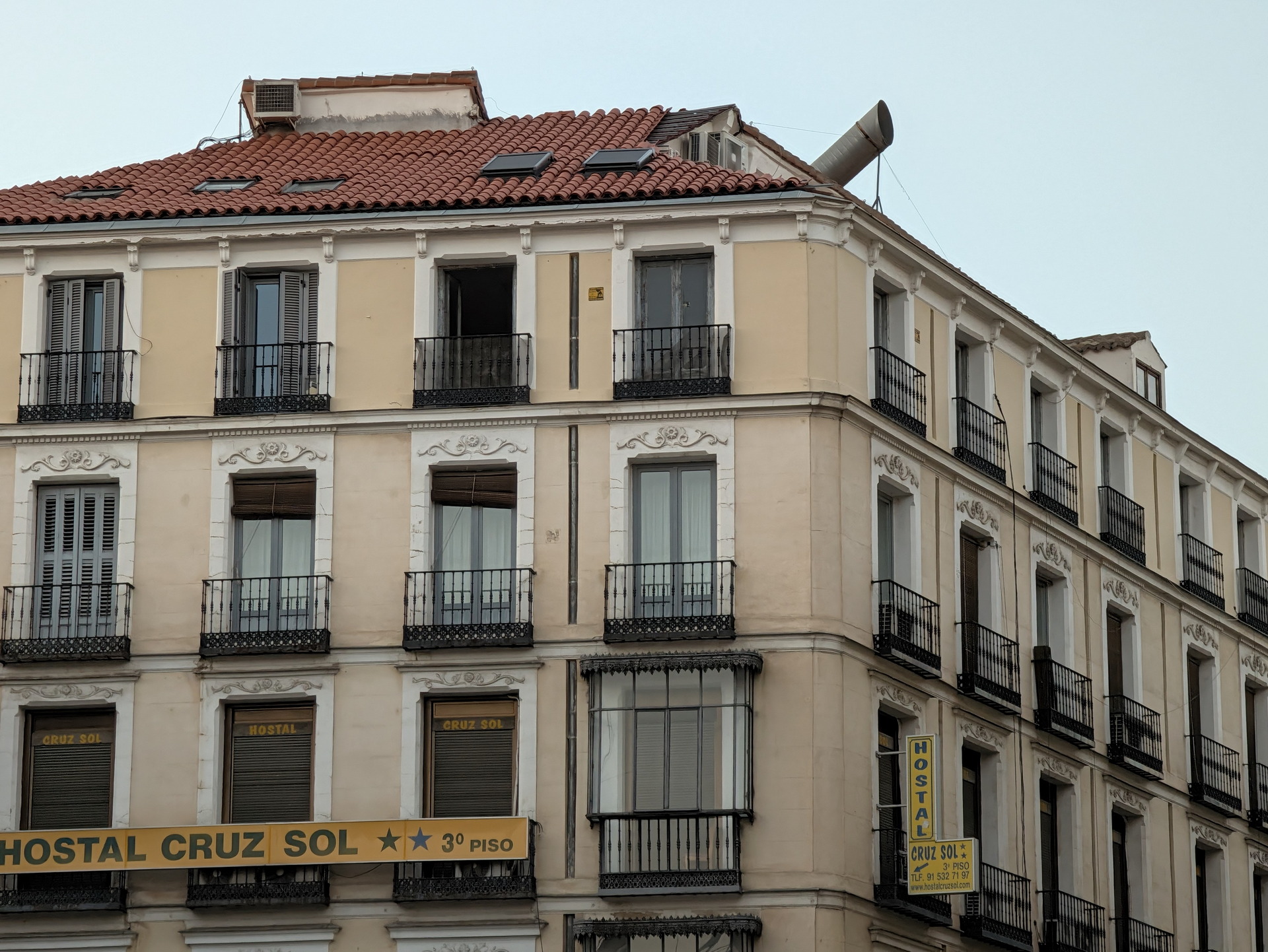 Edificio con letrero de “Hostal Cruz Sol”. Arquitectura clásica con balcones y ventanas en el centro urbano.