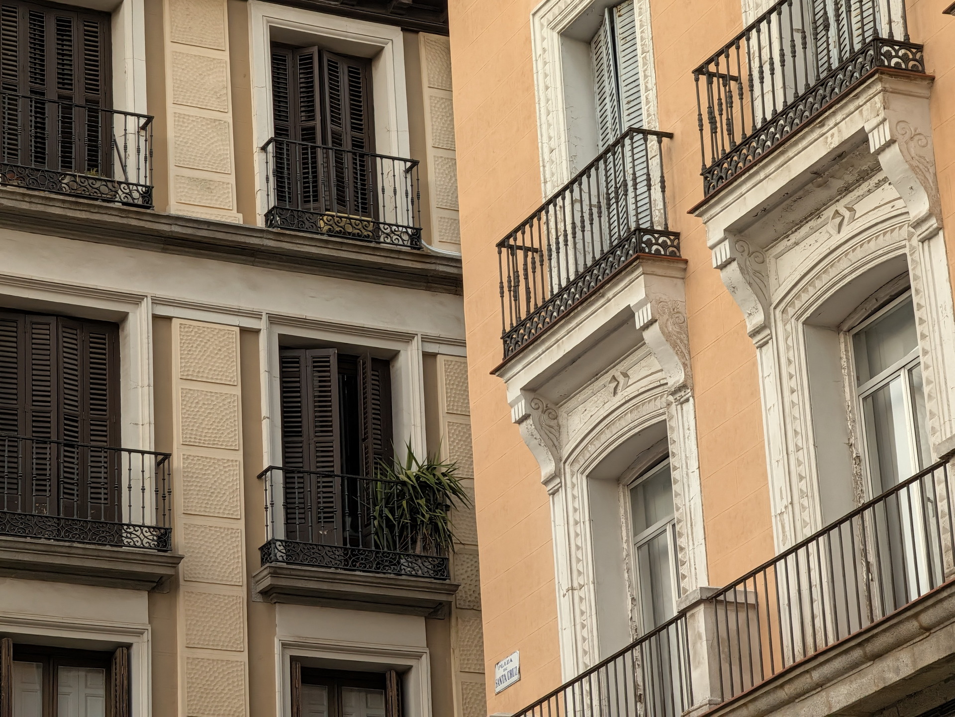 Fachadas clásicas de edificios en una calle española con balcones y persianas de madera.