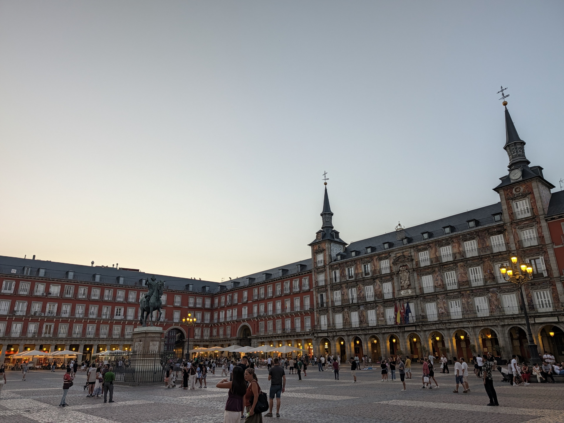 Plaza Mayor de Madrid al atardecer con turistas paseando y edificio histórico de fondo.
