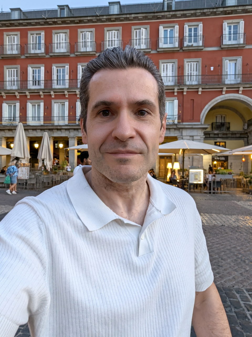 Persona en la Plaza Mayor de Madrid, edificio rojo como fondo.