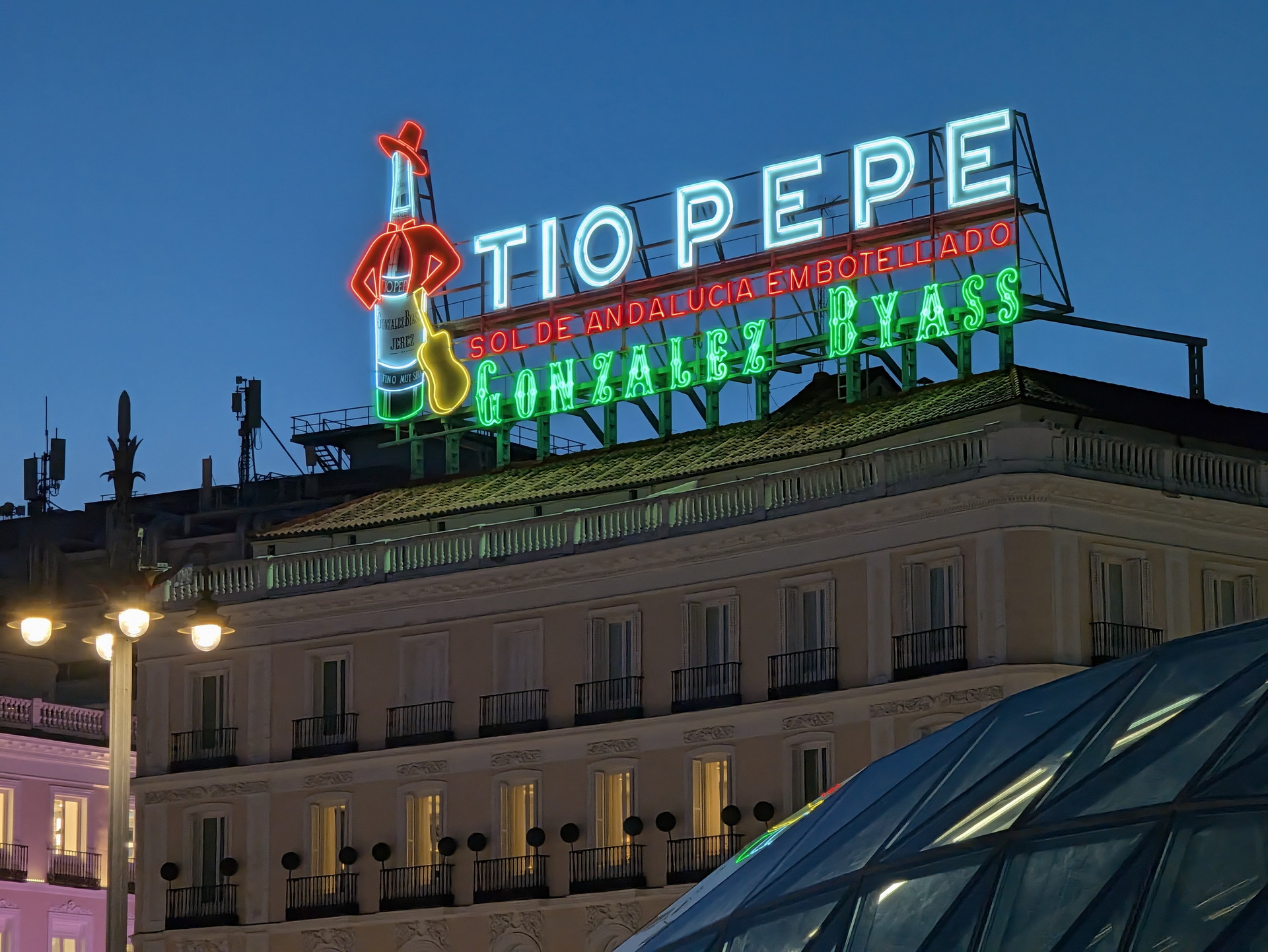 Letrero luminoso de Tío Pepe sobre edificio al anochecer en la Puerta del Sol, Madrid. Icono turístico de la ciudad.