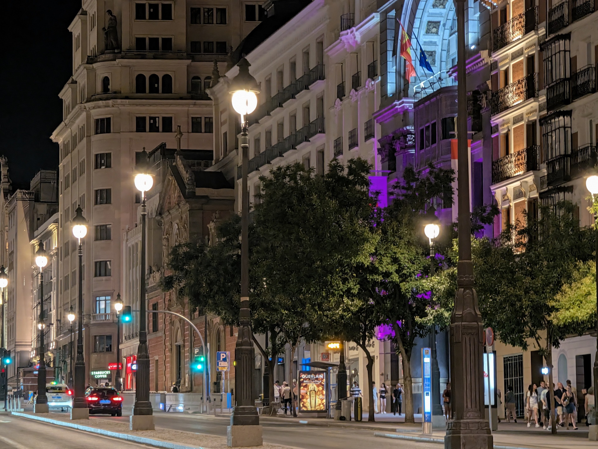 Calle iluminada en Madrid por la noche, con edificios históricos y luces urbanas.