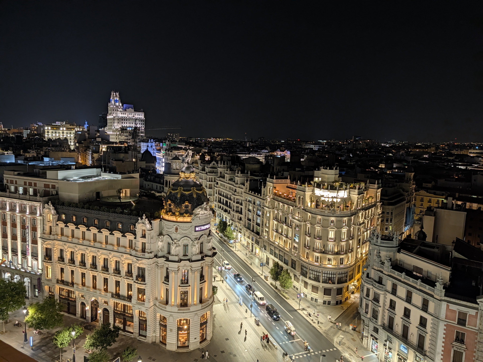 Vista nocturna de la Gran Vía de Madrid, con el edificio Metrópolis iluminado, destacando la arquitectura urbana.