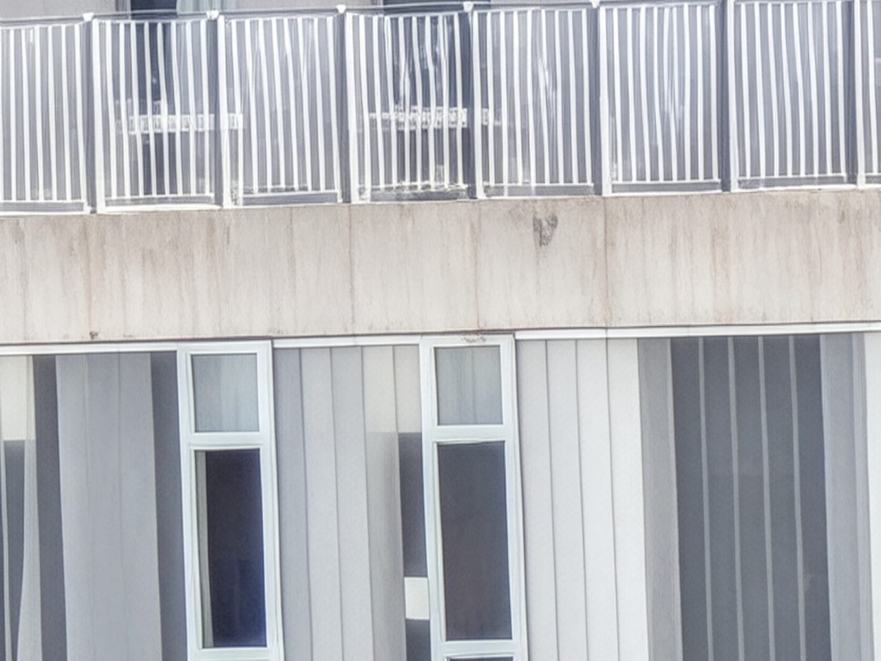 Fachada moderna con barandas y ventanas grandes en un edificio contemporáneo.