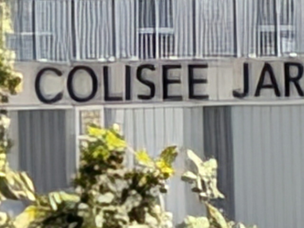 Fachada del edificio con el nombre Colisee Jar, rodeado de árboles.