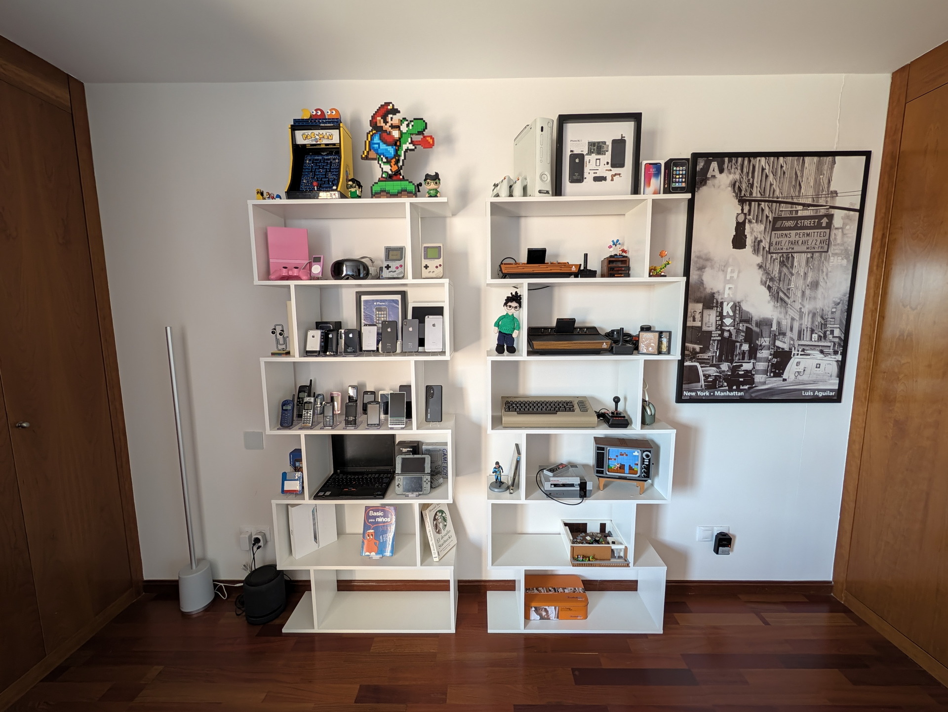 Estantería con artículos retro de tecnología y videojuegos, incluyendo consolas, teléfonos antiguos y decoraciones geek.