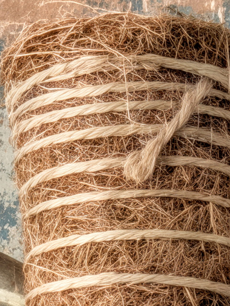 Rollo de hilo de yute natural sobre fondo texturizado. Ideal para artesanía y decoración ecológica.