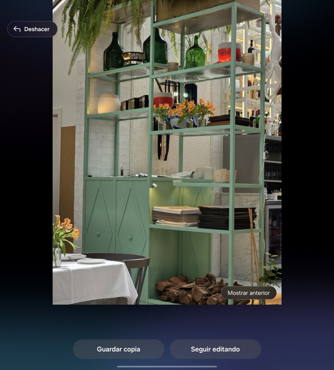 Estantería verde con plantas y jarrones modernos en comedor decorado, mesa con flores y platos preparados.