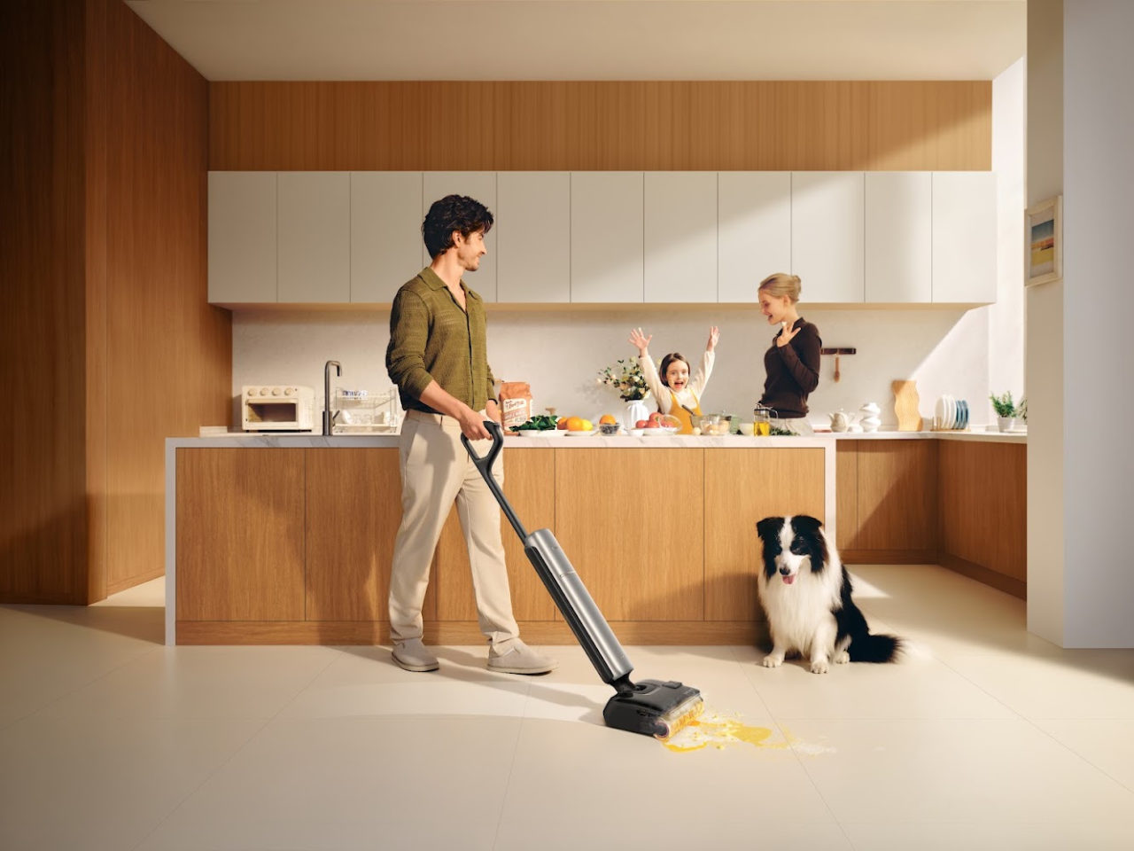 Hombre limpiando piso en cocina moderna con aspiradora, perro y familia en la encimera alegrándose.