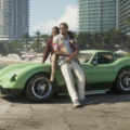 Hombre y mujer con ropa tropical posan con un coche verde en la playa, rascacielos de fondo, ambiente soleado.