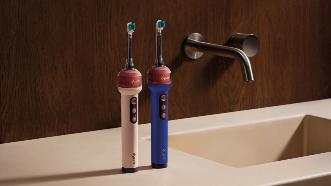 Dos cepillos de dientes eléctricos en un baño moderno sobre un lavabo beige con pared marrón de fondo.