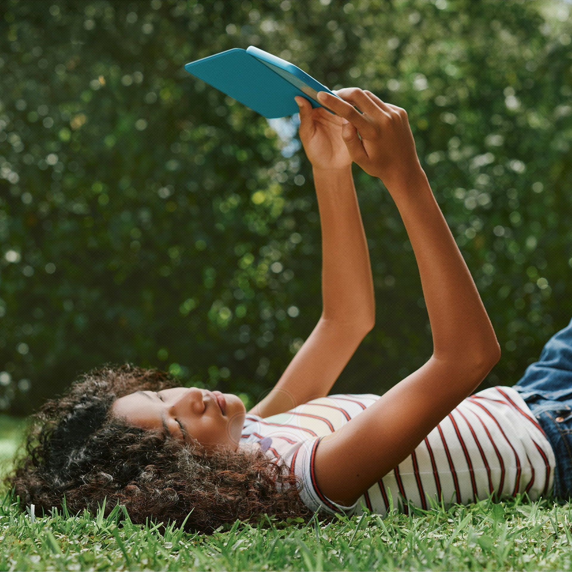 Joven leyendo un libro en un jardín, disfrutando de un día soleado y relajante en la naturaleza.