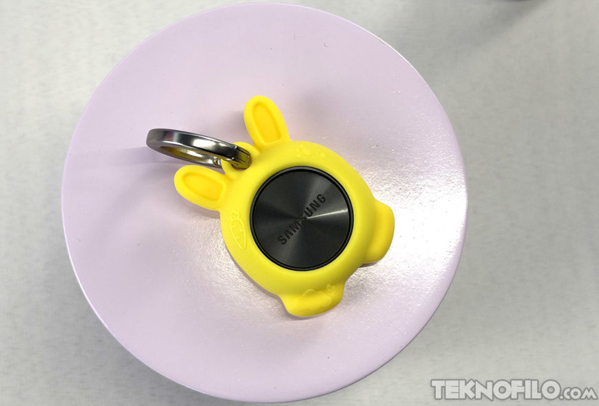 Samsung rectifica: SmartTag3 funciona con iPhone, pero sigue excluyendo a otros Android Llavero amarillo con dispositivo de seguimiento Samsung en soporte circular lilac. Ideal para localizar objetos.