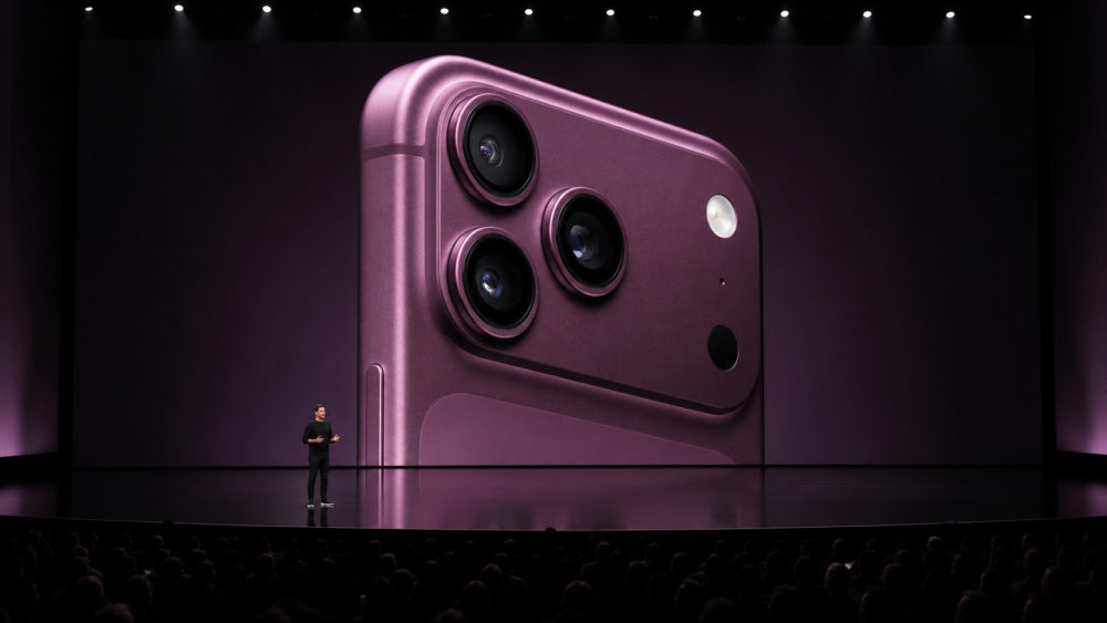 El iPhone 18 Pro podría estrenar cinco funciones de cámara realmente profesionales Presentación de un nuevo smartphone con diseño violeta y tres cámaras traseras en un evento tecnológico.