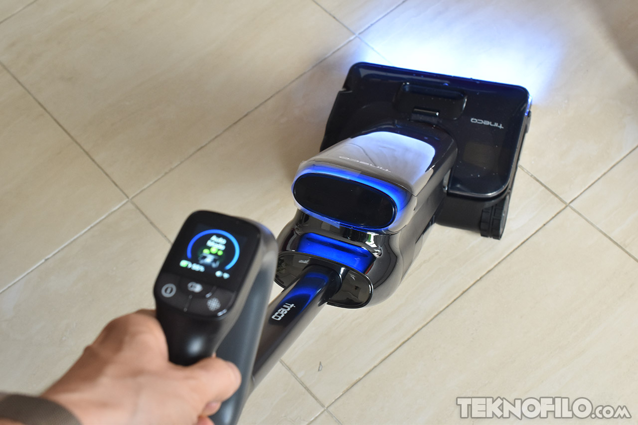 Aspiradora inteligente en uso sobre piso de baldosas, mostrando pantalla de control y luces LED.