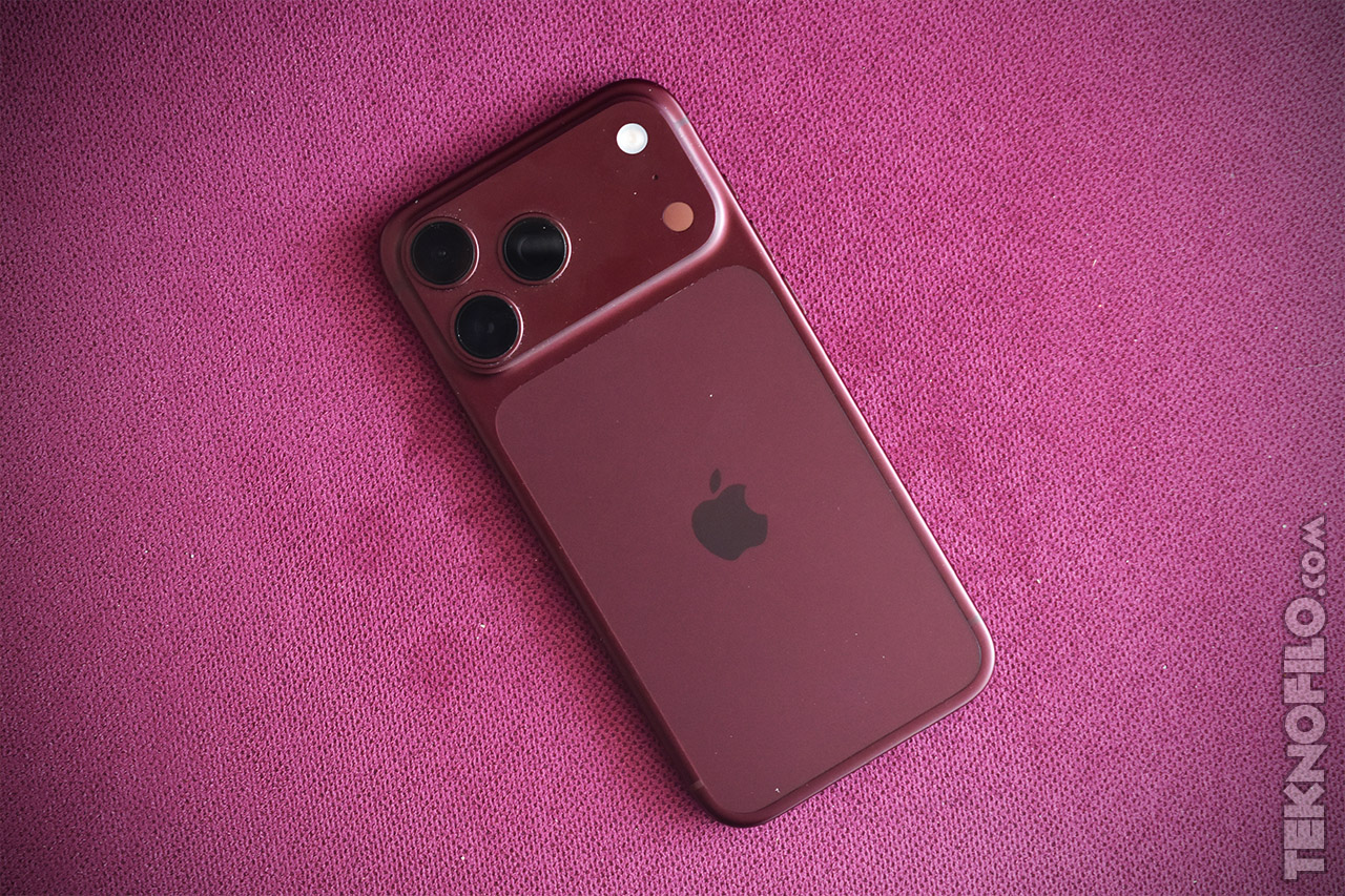 Teléfono inteligente rojo con triple cámara en una superficie púrpura.