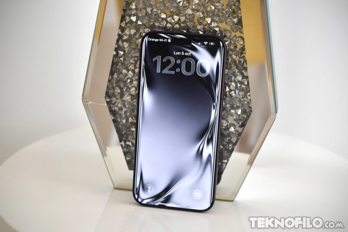 Análisis del iPhone 18 Pro Max a fondo y opinión Teléfono móvil en exhibición con pantalla iluminada a las 12:00, rodeado de fondo decorativo brillante.