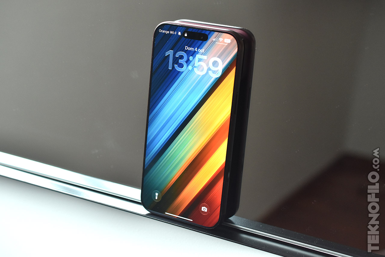 Smartphone moderno con fondo de pantalla colorido, reflejado en una superficie de espejo. Pantalla activa mostrando la hora.