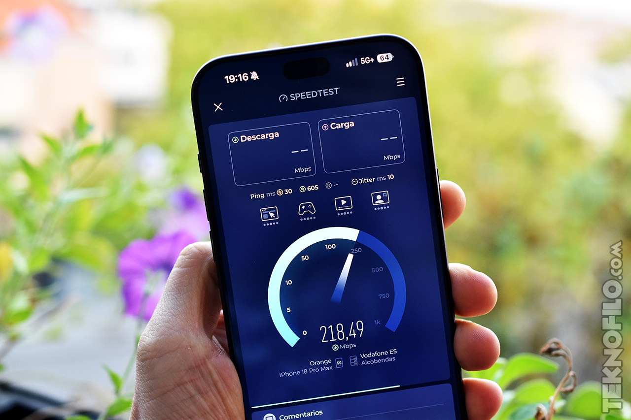 Pantalla de móvil mostrando prueba de velocidad de internet con 218,49 Mbps de descarga y red 5G, al aire libre.