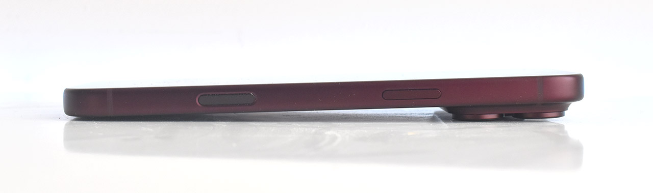 Smartphone rojo visto de perfil sobre superficie blanca, mostrando botones laterales y cámaras traseras.