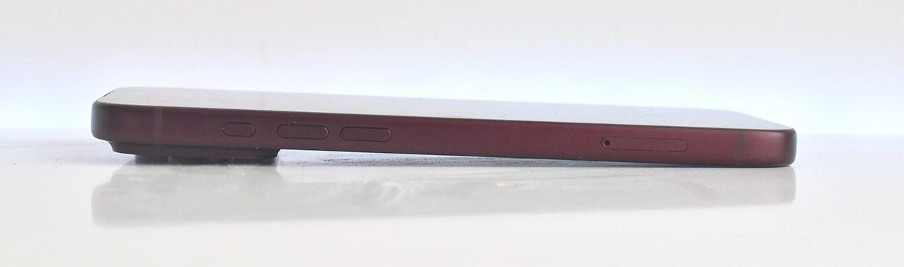 Lateral de un smartphone rojo con botones de control y bandeja SIM sobre superficie blanca.
