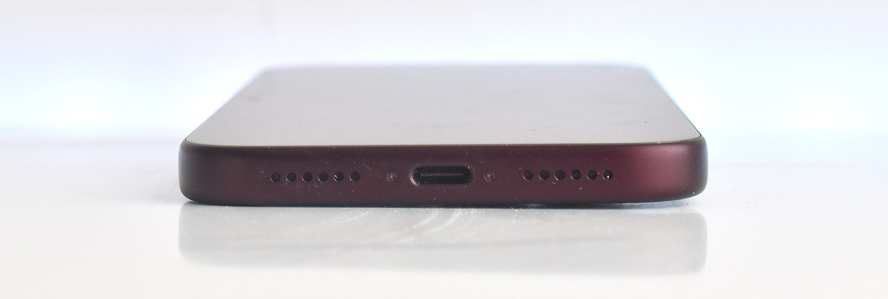 Parte inferior de un smartphone con puerto de carga USB-C y altavoces a cada lado sobre fondo blanco.