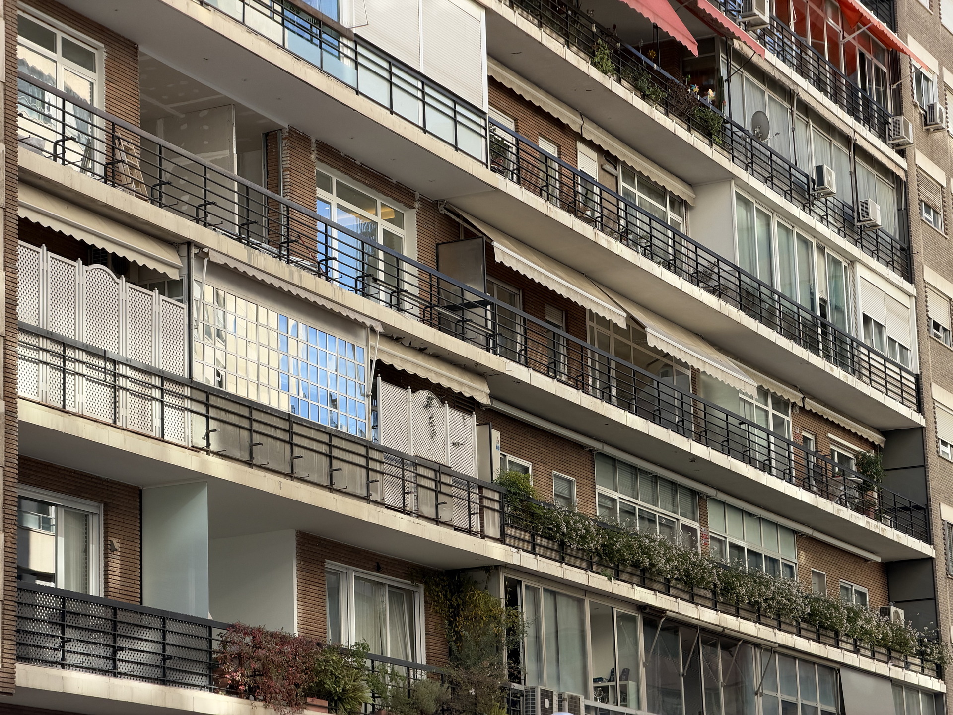 Fachada de edificio de apartamentos con balcones y jardineras, típica arquitectura urbana.