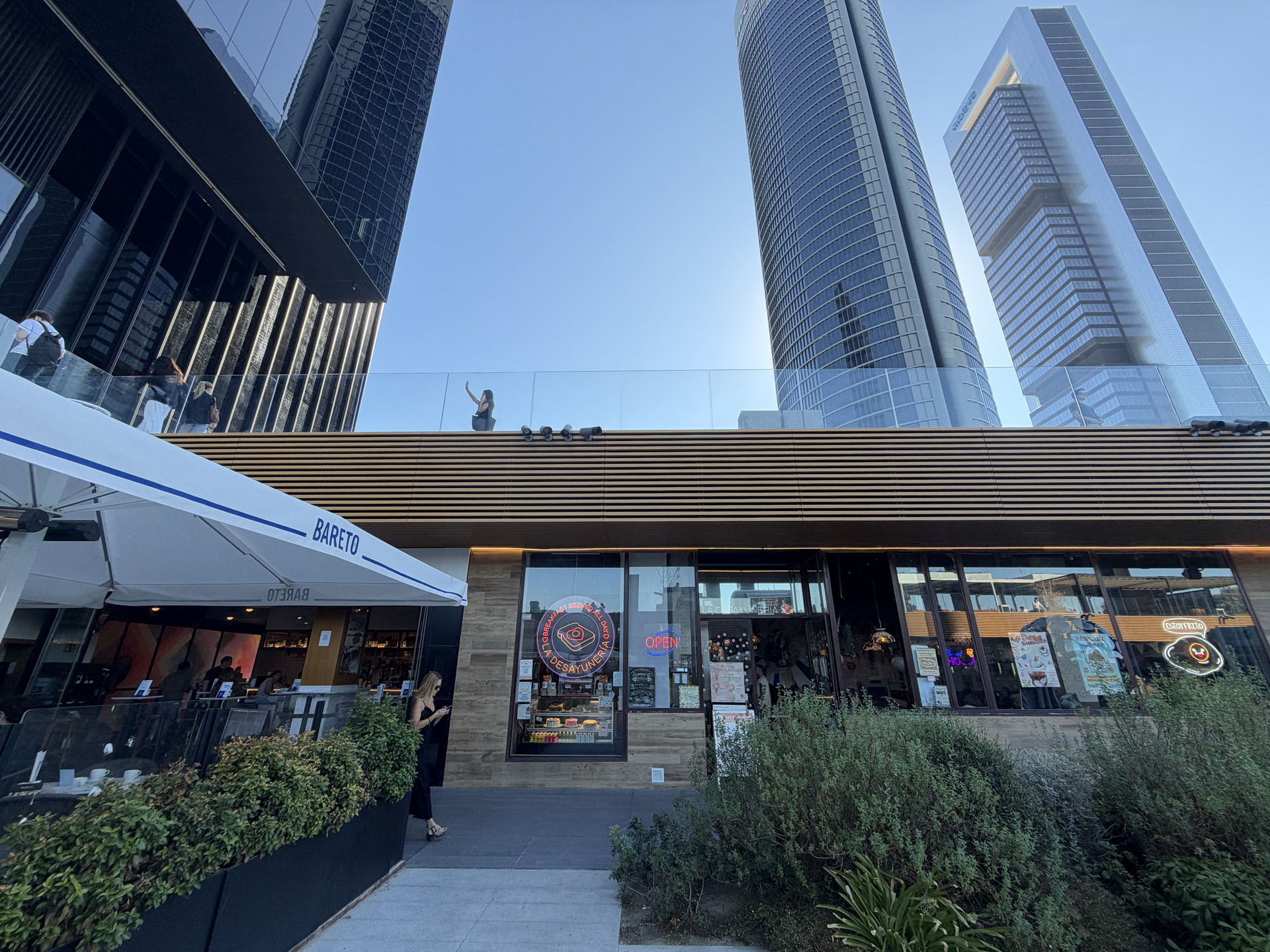 Vista de moderno rascacielos y cafetería Bareto al aire libre en un día soleado en la ciudad.