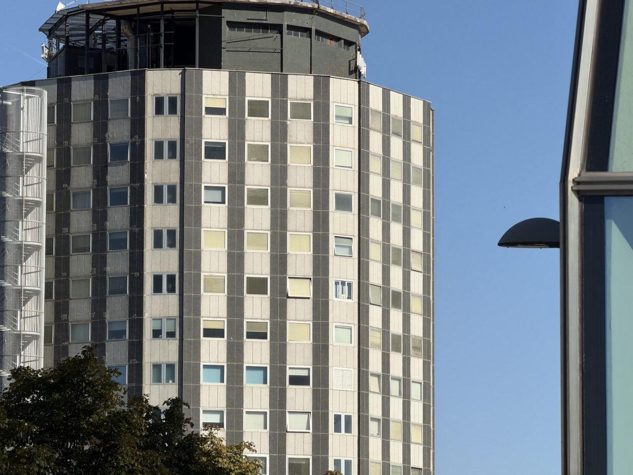 Edificio de apartamentos altos con ventanas cuadradas bajo un cielo azul despejado.
