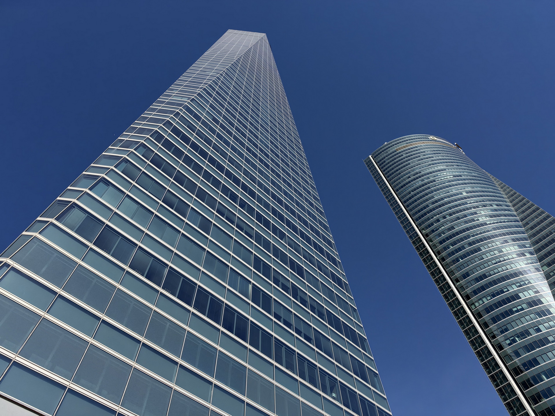 Rascacielos modernos bajo un cielo azul en perspectiva ascendente, arquitectura urbana de vanguardia.