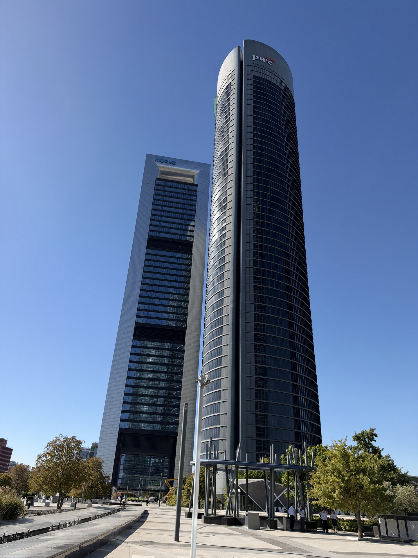 Torres altas en Madrid bajo un cielo azul, rodeadas de árboles. Arquitectura moderna y urbana.