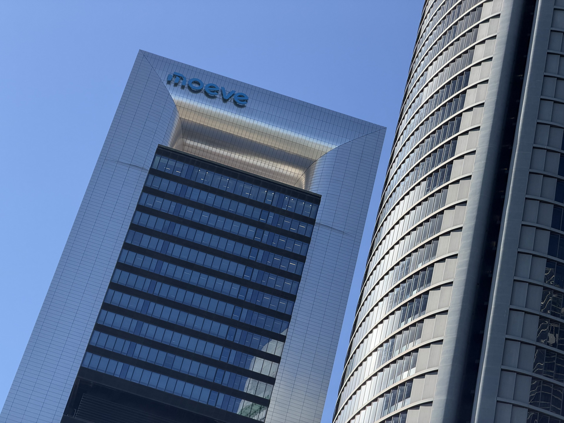 Rascacielos modernos en cielo azul, con el logo noeve visible en el edificio principal, arquitectura urbana.